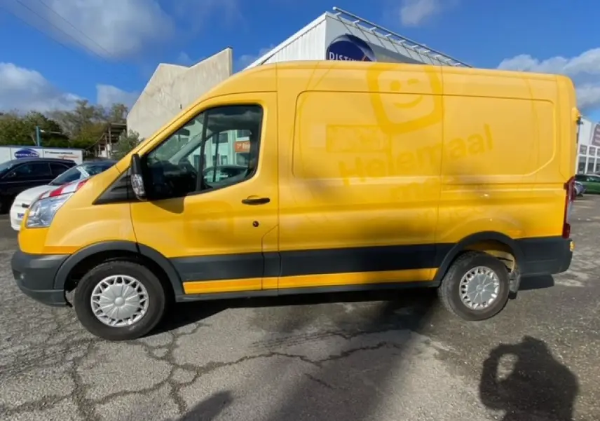 Fourgon Ford Transit L3H2 orange vu de profil côté gauche sur un parking ensoleillé.