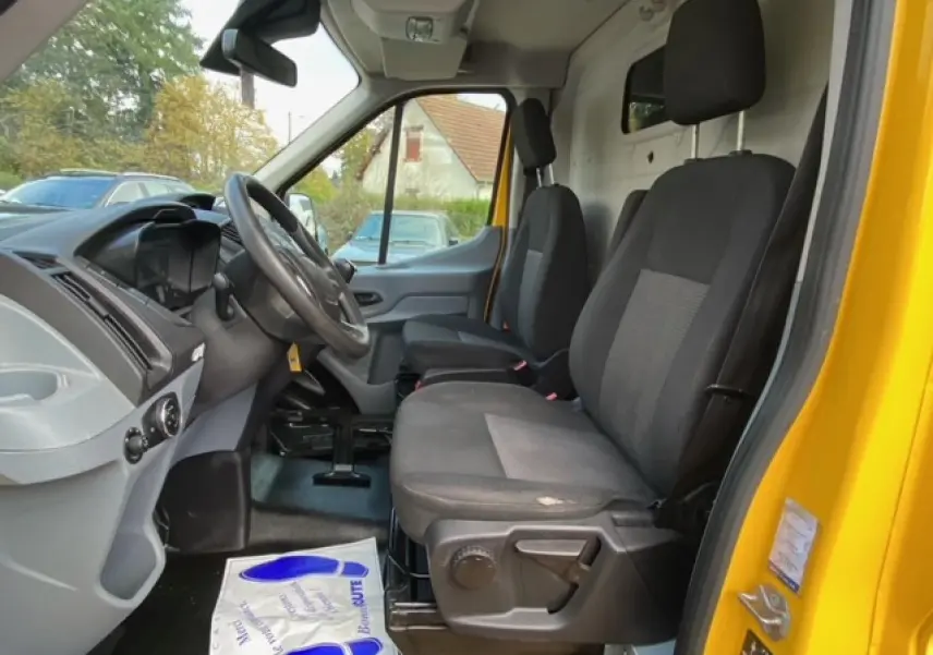 Intérieur du Ford Transit Fourgon orange 2015, vue côté conducteur montrant les sièges avant et le tableau de bord.