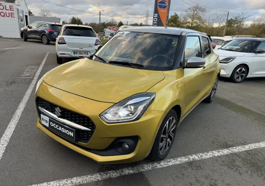 Suzuki Swift 1.2 Pack Auto hybride essence jaune avec toit gris, vue 3/4 avant droit sur parking extérieur.