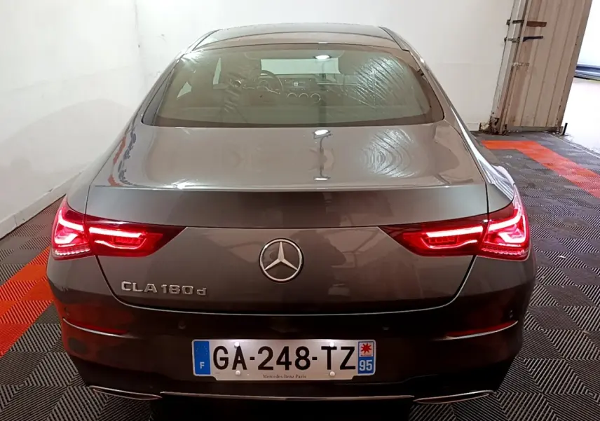 Vue arrière d'une Mercedes CLA 180 d gris clair avec feux LED allumés dans un garage fermé.