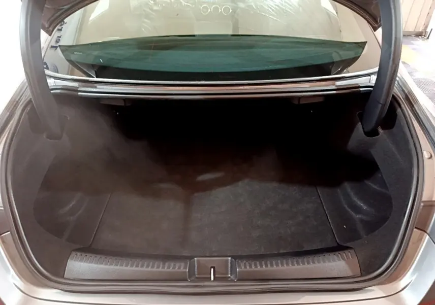 Coffre ouvert d'une Mercedes CLA 180 d gris clair, vue arrière montrant l'espace de rangement vide.
