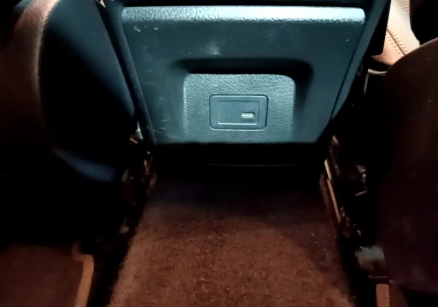 Vue rapprochée de la prise USB arrière entre les sièges noirs de la Mercedes CLA 180 d Business Line gris clair.