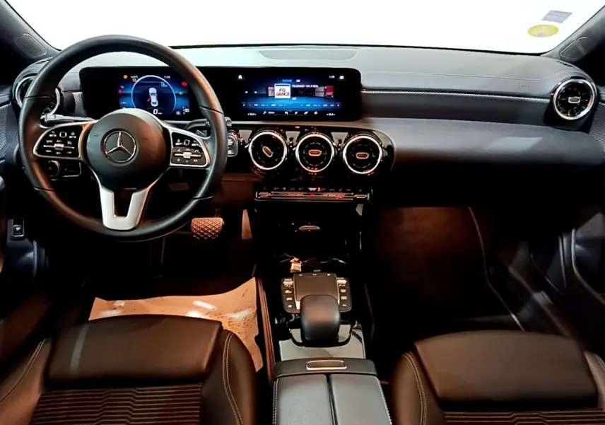 Vue intérieure avant de la Mercedes CLA 180 d Business Line 2021, tableau de bord noir avec écran tactile et volant multifonctions.