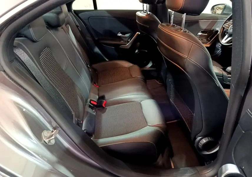 Vue intérieure côté arrière gauche sur les sièges noirs en cuir et tissu du Mercedes CLA 180 d Business Line gris clair.
