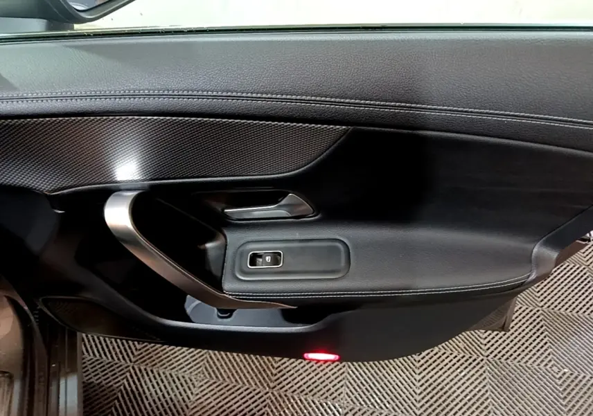 Gros plan sur la porte intérieure côté gauche d'une Mercedes CLA 180 d Business Line 2021 en gris clair, avec insert carbone et éclairage rouge.
