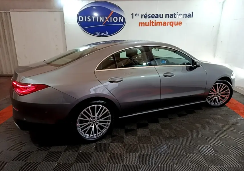 Vue latérale droite d'une Mercedes Classe CLA 180 d Business Line gris clair avec jantes alliage et feux arrière LED allumés.