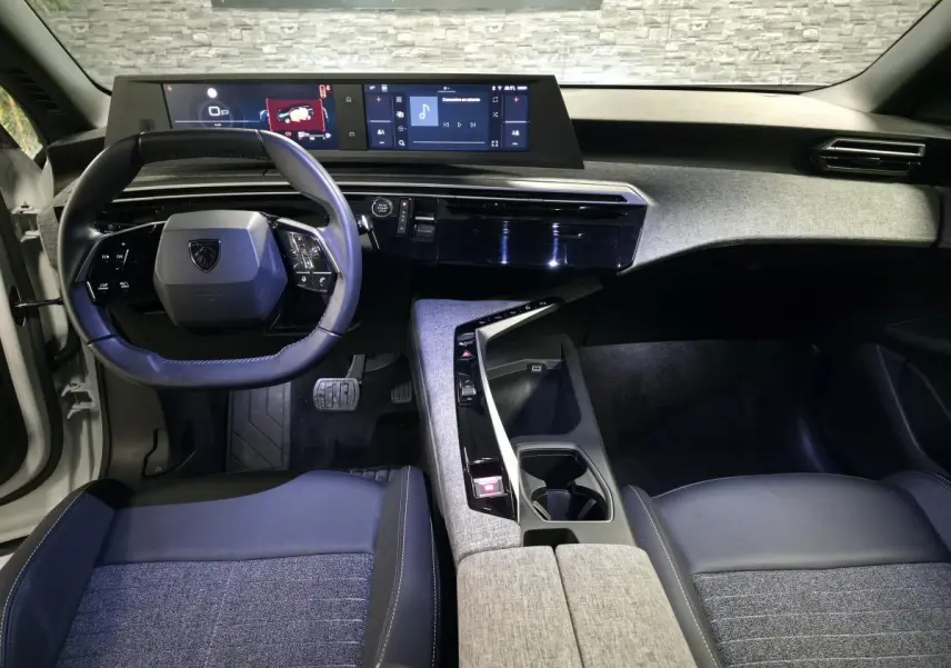 Vue intérieure avant du Peugeot 5008 2025, tableau de bord noir avec double écran HD et volant compact cuir.