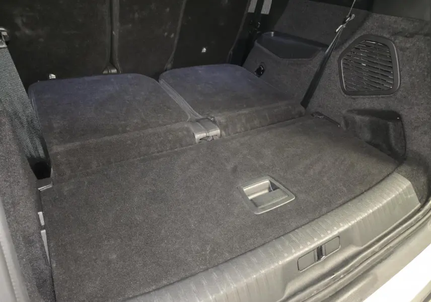 Vue du coffre arrière du Peugeot 5008 blanc 2025 avec banquette rabattue et revêtement noir.