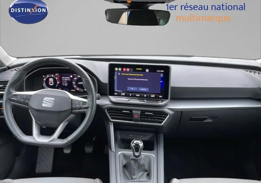 Vue intérieure frontale du poste de conduite du SEAT LEON gris magnétique, avec volant multifonction et écran tactile central.