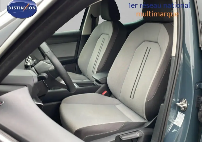 Vue intérieure côté conducteur montrant les sièges tissu gris clair et foncé d'une SEAT LEON 2.0 TDI 2025 gris magnétique métal.