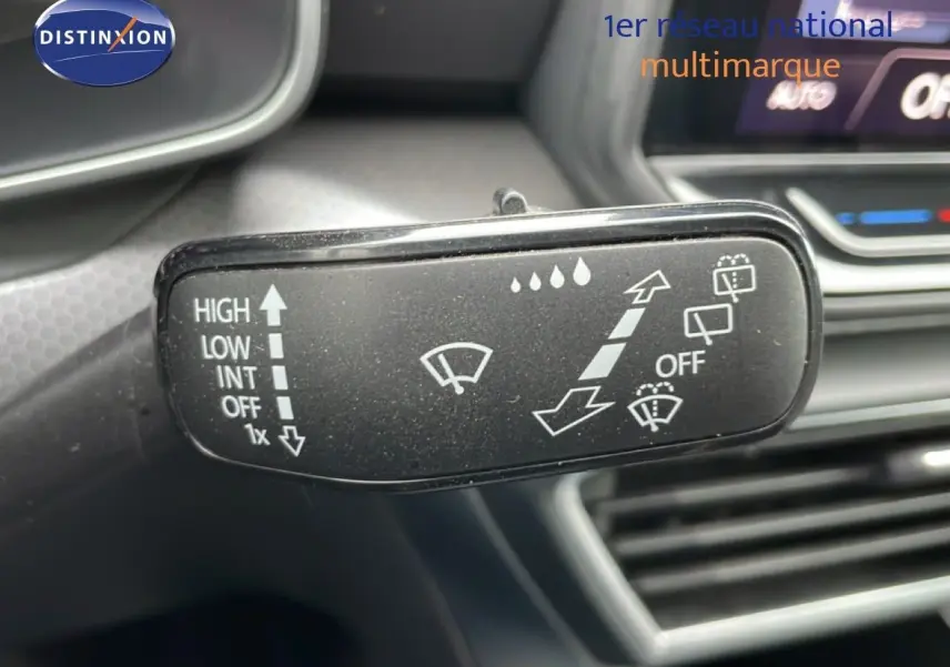 Gros plan sur le commodo d’essuie-glace noir à l’intérieur d’une SEAT LEON gris magnétique, avec tableau de bord en arrière-plan flou.