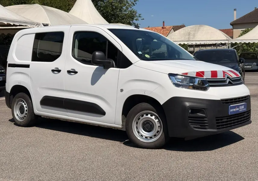 Vue 3/4 avant gauche d’un Citroën Berlingo Van blanc avec marquage rouge sur le capot et protections noires sur les bas de caisse.