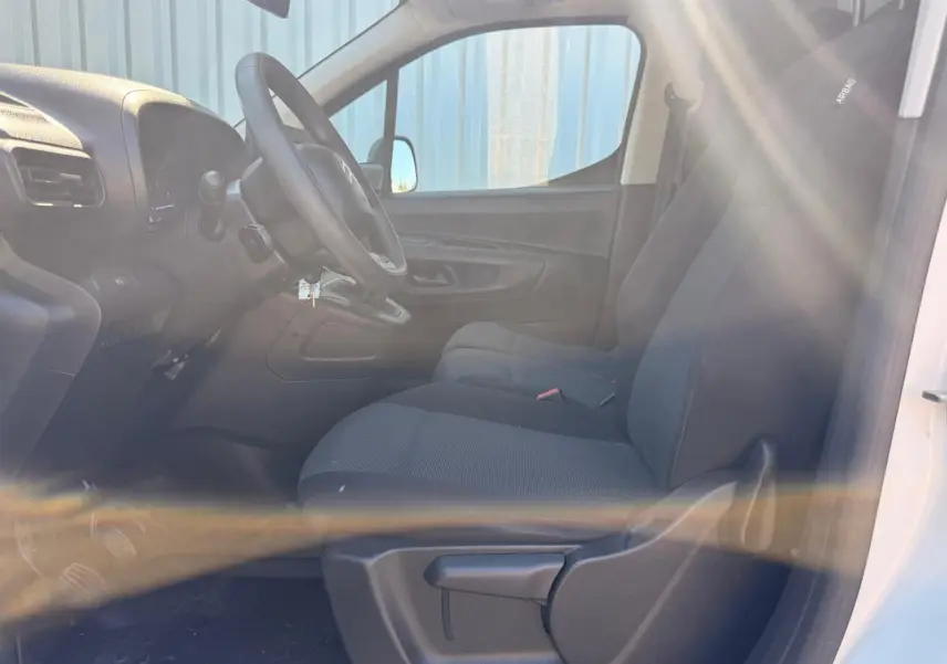 Vue intérieure côté conducteur du Citroën Berlingo blanc 2020, montrant les sièges en tissu et le tableau de bord.