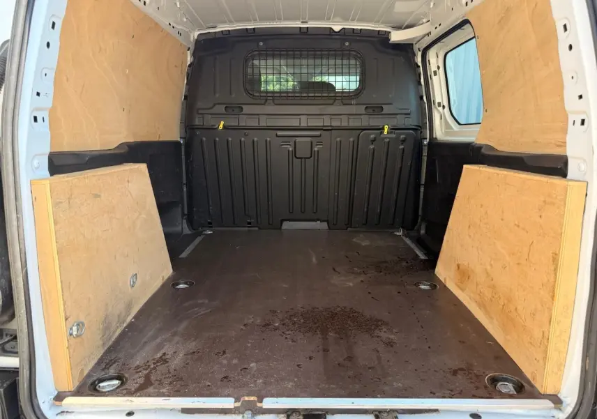 Intérieur du coffre du Citroën Berlingo Van blanc 2020, vue arrière ouverte avec parois en bois et cloison métallique noire.