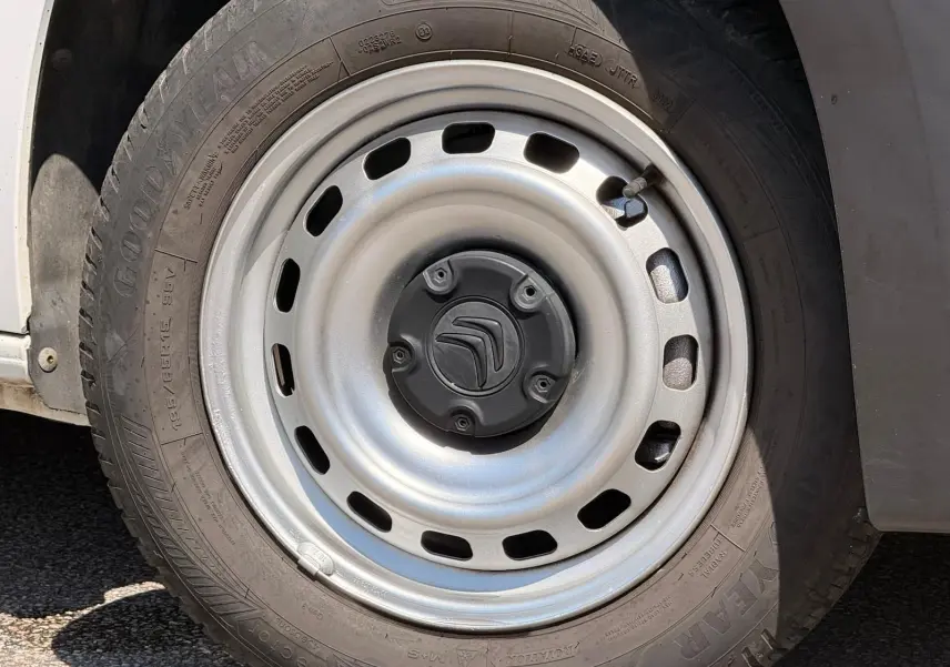 Gros plan sur la roue avant gauche du Citroën Berlingo blanc, jante acier avec logo Citroën au centre.