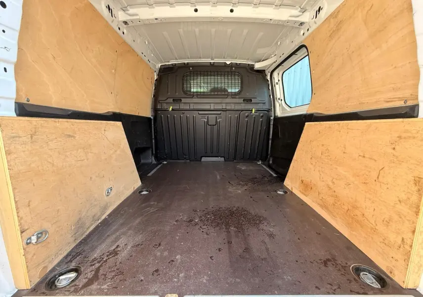 Intérieur du coffre du Citroën Berlingo Van blanc, vue de l'arrière montrant le plancher et les parois en bois.