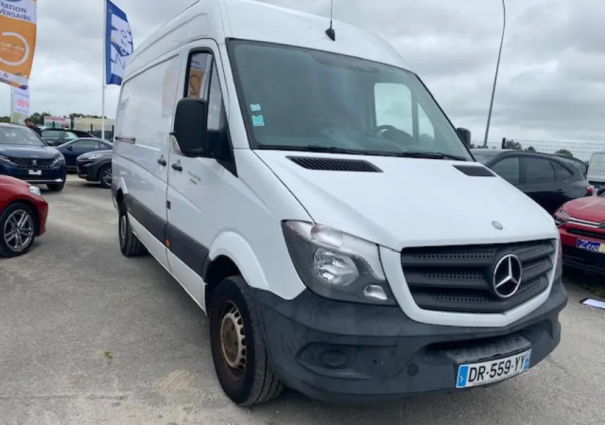 Vue 3/4 avant d'un Mercedes Sprinter blanc de 2015 avec pare-chocs noir et plaques françaises sur parking.