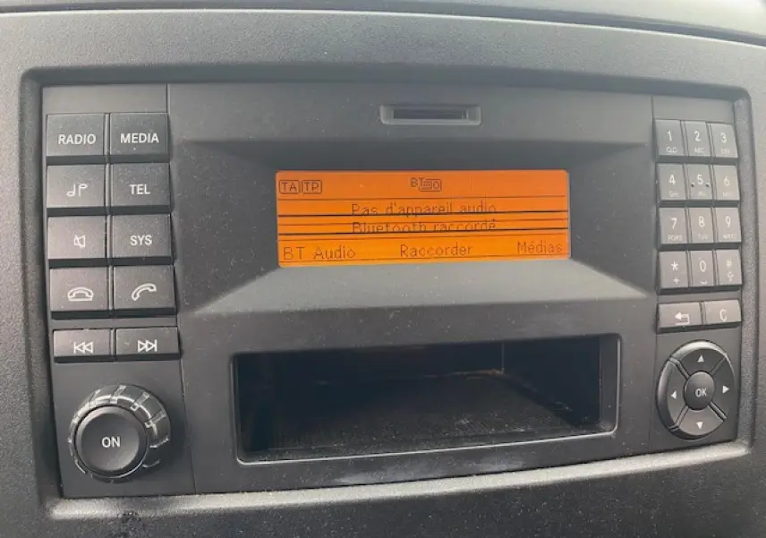 Affichage central orange du système audio du Mercedes Sprinter Fourgon blanc, vue rapprochée du tableau de bord.