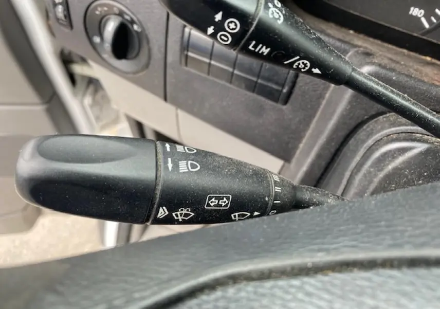 Gros plan sur la commande de clignotants et régulateur de vitesse du tableau de bord d'un Mercedes Sprinter blanc de 2015.