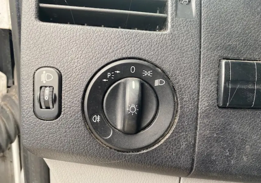Gros plan sur le bouton de commande des phares du tableau de bord noir du Mercedes Sprinter Fourgon blanc de 2015.