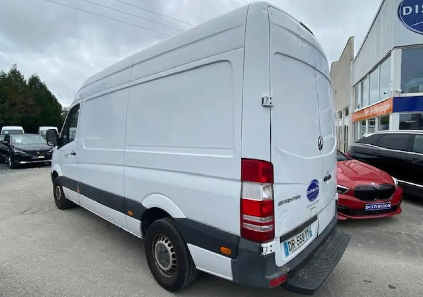 Vue 3/4 arrière droite d'un fourgon Mercedes Sprinter blanc de 2015 avec porte arrière fermée et feux rouges visibles.