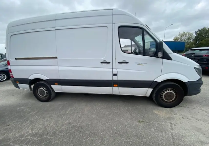 Profil côté droit d'un fourgon Mercedes Sprinter blanc de 2015 avec bande noire et jantes acier simples.
