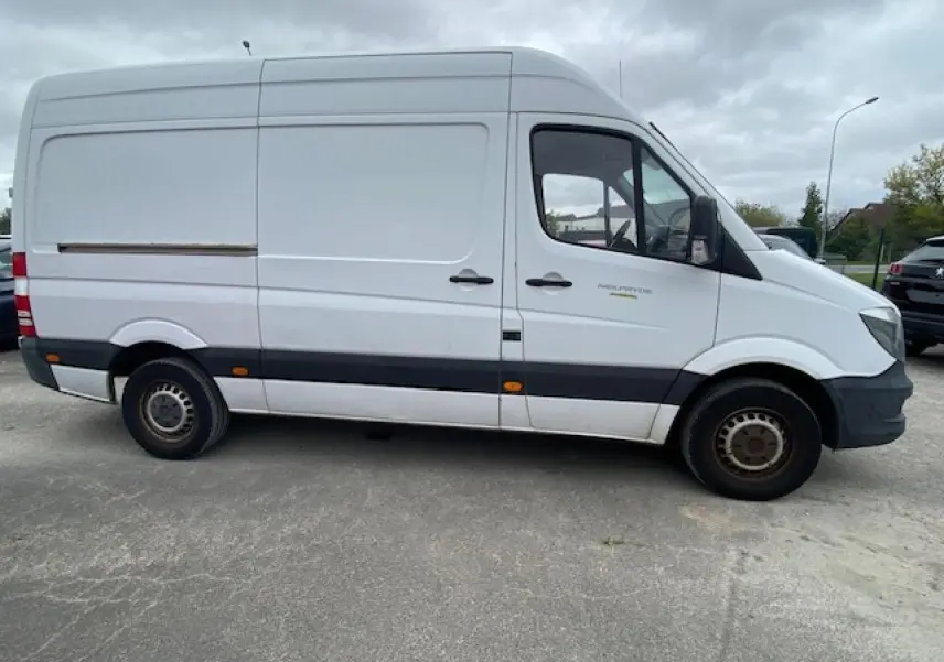 Profil côté gauche d'un fourgon Mercedes Sprinter blanc 2015 avec bande noire et feux latéraux orange visibles.