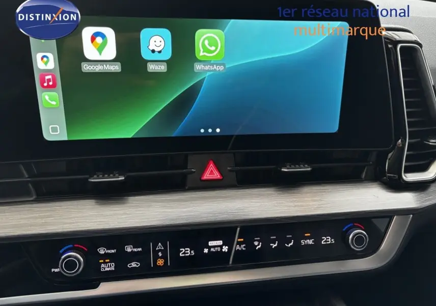 Vue rapprochée de la console centrale du Kia Sportage blanc nacré, avec écran tactile et commandes climatisation.