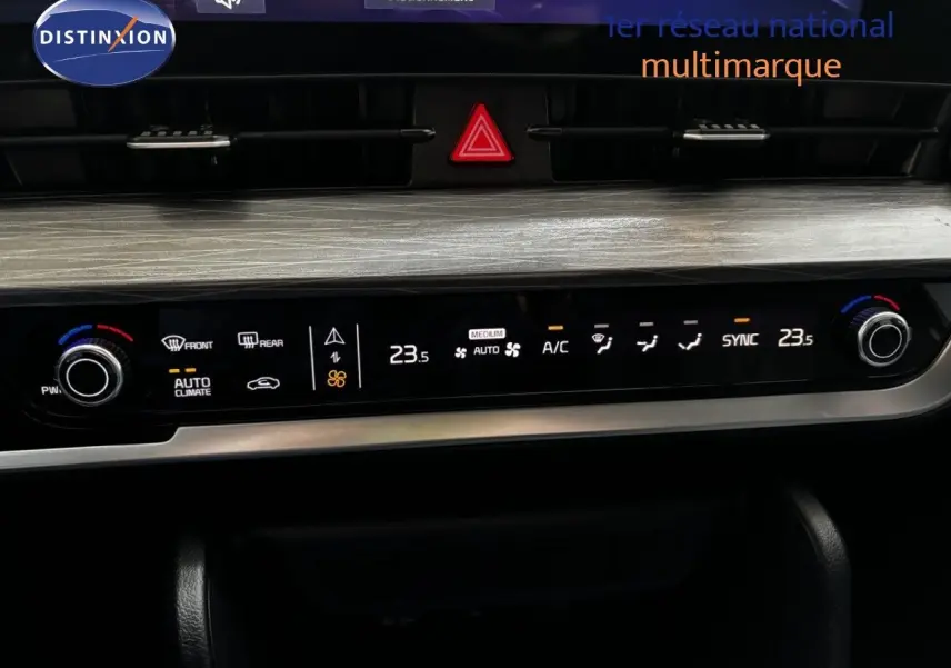 Tableau de bord du Kia Sportage blanc nacré, vue centrée sur la console de climatisation digitale avec finition bois clair.