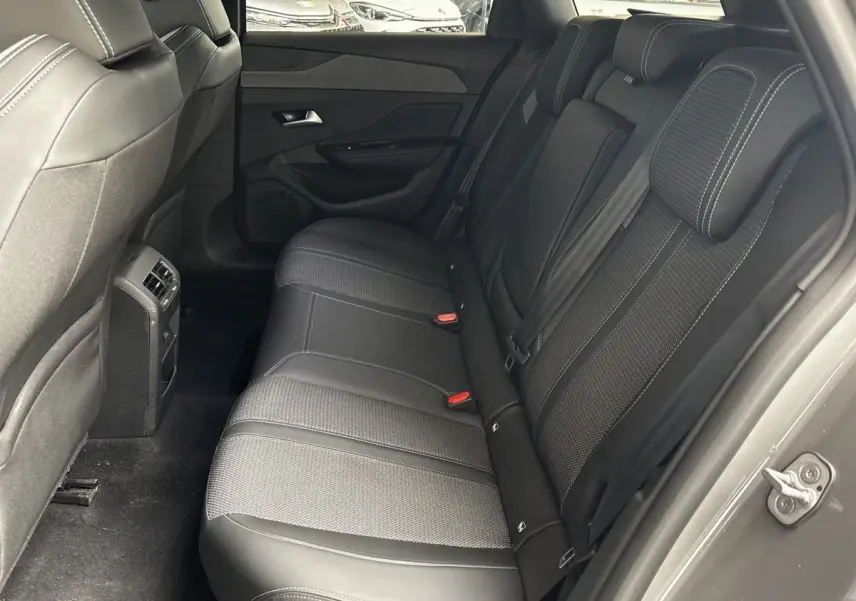 Vue intérieure arrière droite des sièges noirs en tissu et cuir de la Peugeot 308 PureTech 130 Allure 2024.