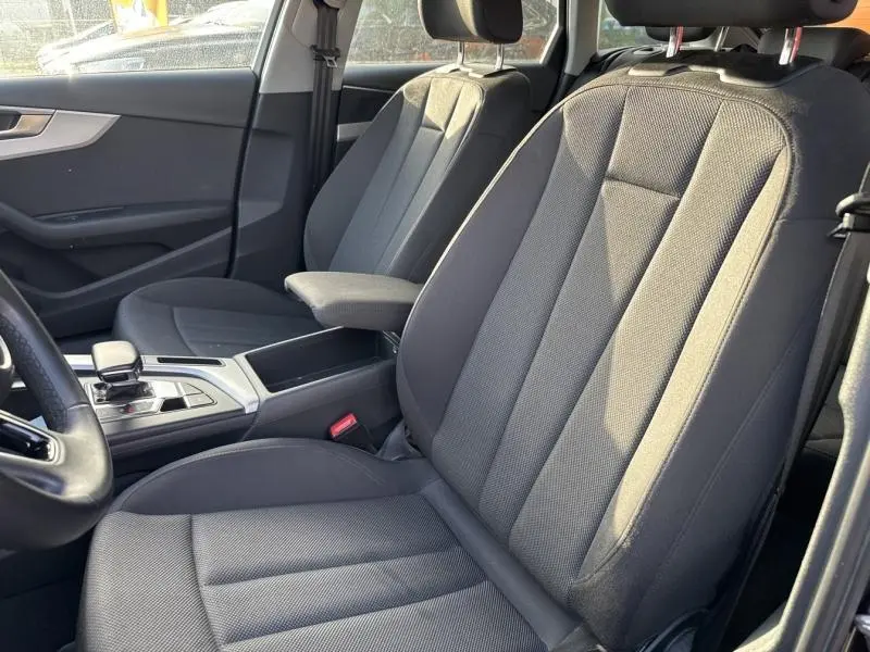 Vue intérieure côté gauche montrant les sièges avant noirs en tissu et l'accoudoir central de l'Audi A4 Avant 2022.