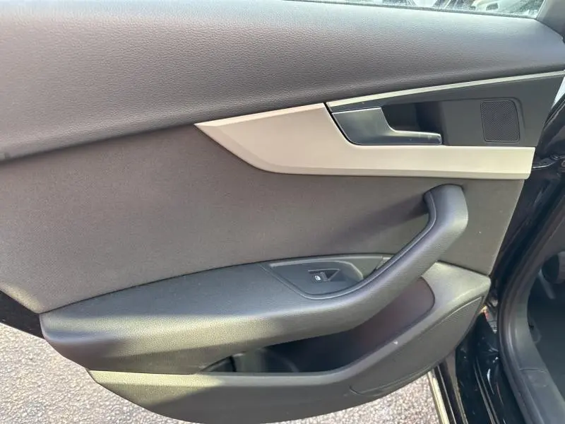 Vue rapprochée de la porte avant droite noire brillante de l'Audi A4 Avant 30 TDI 2022 avec garniture intérieure grise et noire.