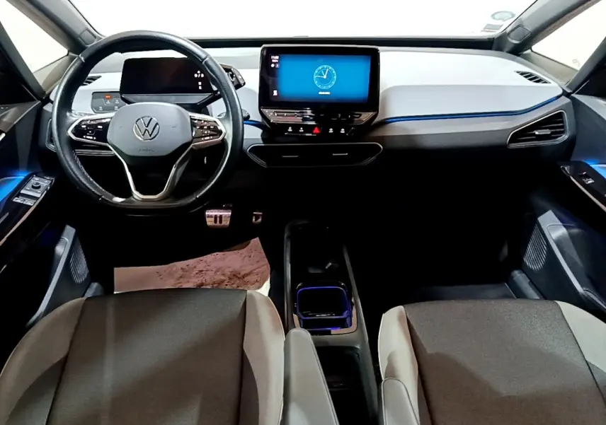 Vue intérieure avant du Volkswagen ID.3 77 kWh Pro S, tableau de bord moderne avec écran tactile central et éclairage d'ambiance bleu.