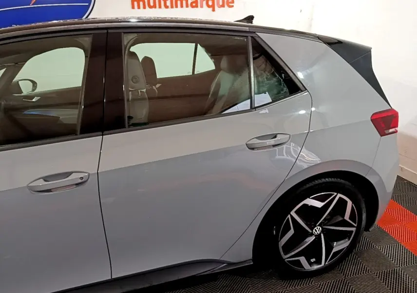 Vue latérale droite du Volkswagen ID.3 gris foncé avec jantes noires et design moderne, en intérieur showroom.