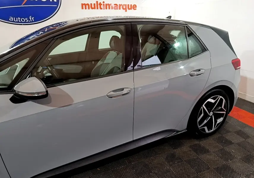 Vue latérale droite d'une Volkswagen ID.3 gris foncé avec jantes noires et toit noir dans un showroom.