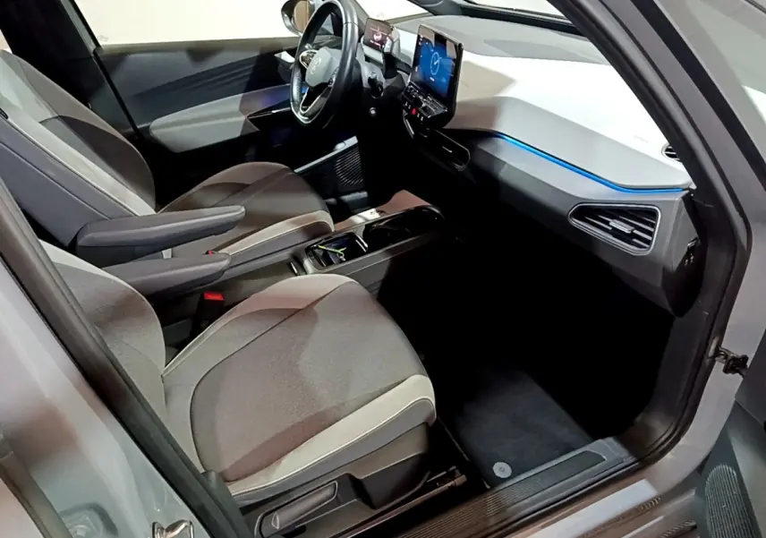 Vue intérieure côté conducteur du Volkswagen ID.3 77 kWh Pro S 2022, avec tableau de bord blanc et éclairage bleu.