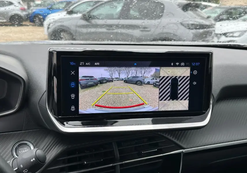 Vue intérieure centrée sur l'écran tactile affichant la caméra de recul du Peugeot 2008 gris avec tableau de bord noir.