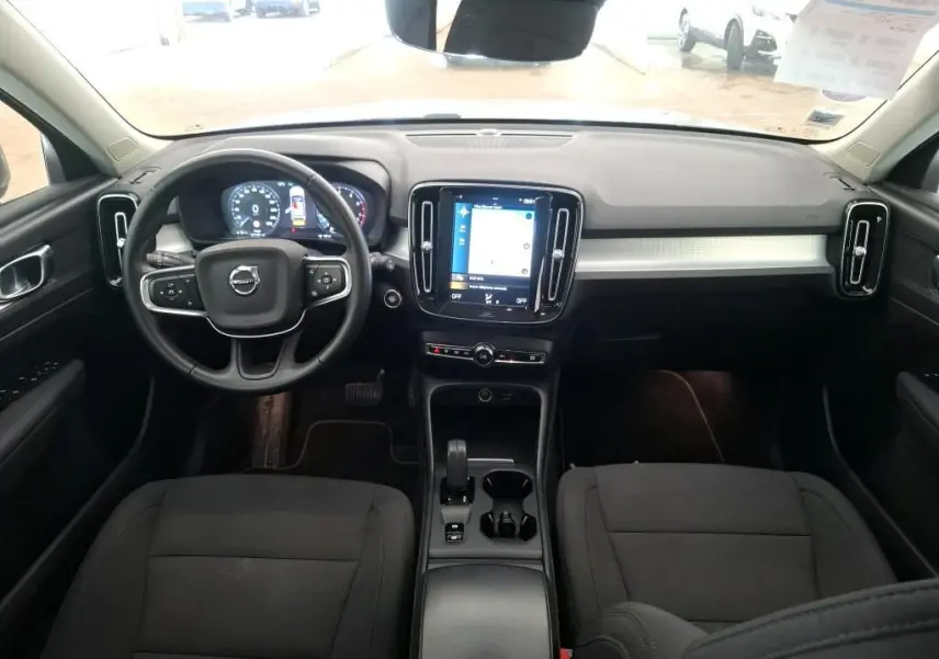 Vue intérieure avant du Volvo XC40 Momentum 2021, tableau de bord noir avec écran tactile central et volant multifonction.