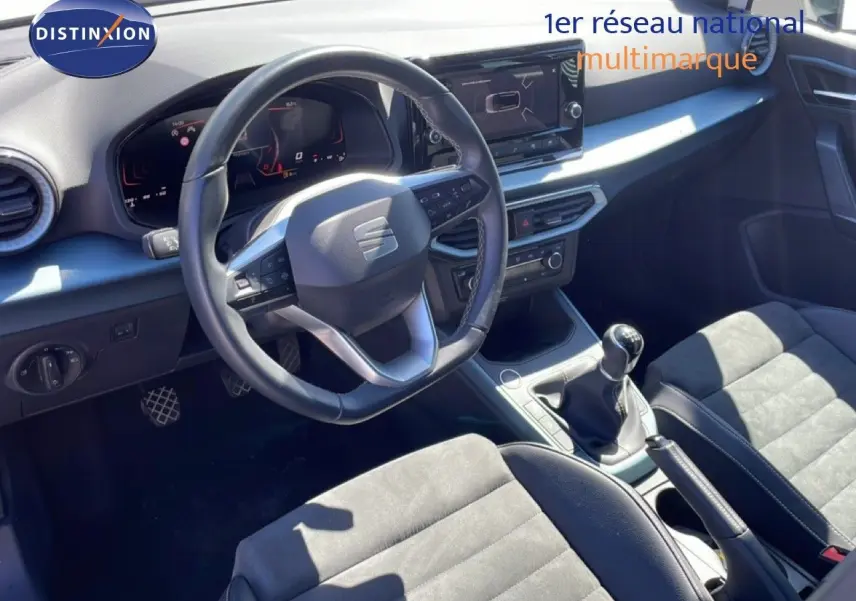 Vue intérieure côté conducteur du SEAT Arona 2025, volant cuir multifonction et levier de vitesses manuelle visibles.