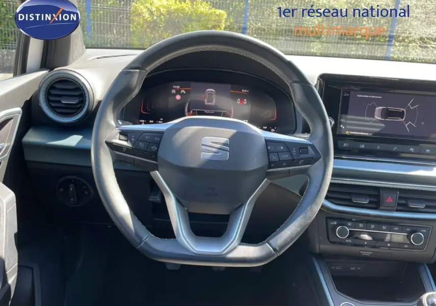 Vue intérieure centrée sur le volant cuir multifonction du SEAT Arona 2025 avec tableau de bord numérique et écran tactile.