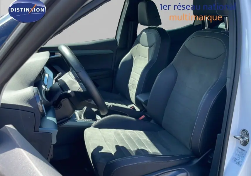 Vue intérieure côté conducteur du SEAT Arona 2025 blanc, montrant les sièges en cuir et alcantara noirs avec volant multifonction.