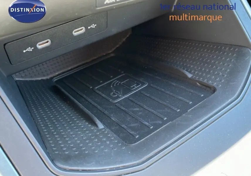 Gros plan sur le chargeur sans fil noir et les ports USB dans l’habitacle du SEAT Arona blanc toit noir, version 2025.