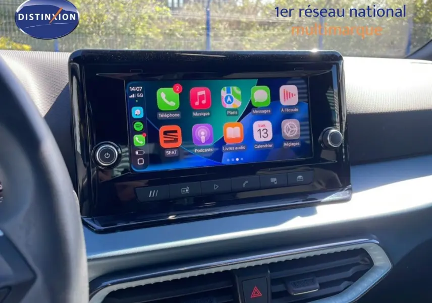 Vue rapprochée de l’écran tactile central du tableau de bord du SEAT Arona blanc avec toit noir, affichant les applications connectées.