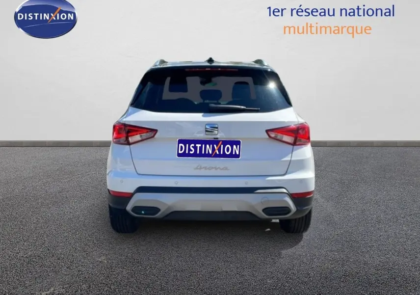 Vue arrière d'un SEAT Arona blanc avec toit noir, montrant les feux arrière et le pare-chocs arrière.