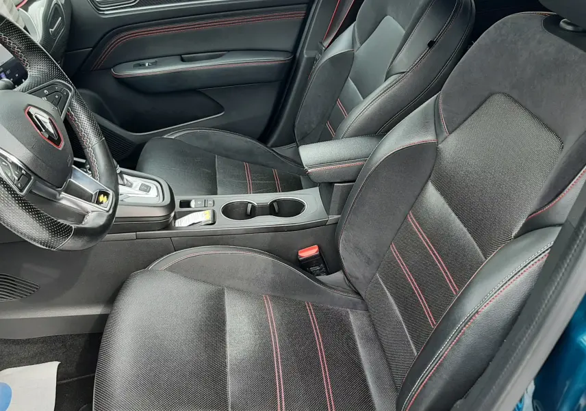 Vue intérieure côté conducteur de la Renault Arkana E-Tech 145ch RS-Line avec sièges noirs et surpiqûres rouges.