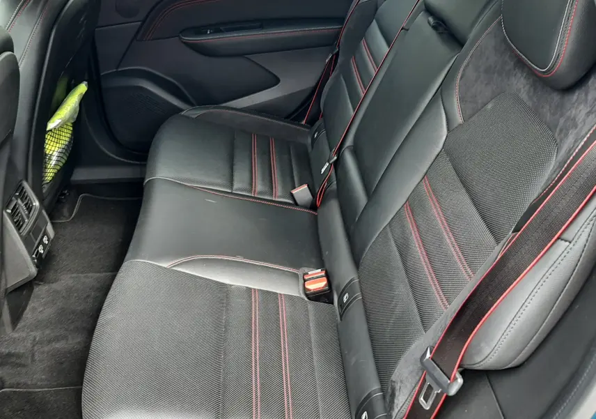 Vue intérieure côté droit des sièges arrière en cuir noir avec surpiqûres rouges du Renault Arkana E-Tech 145ch RS-Line bleu Zanzibar.