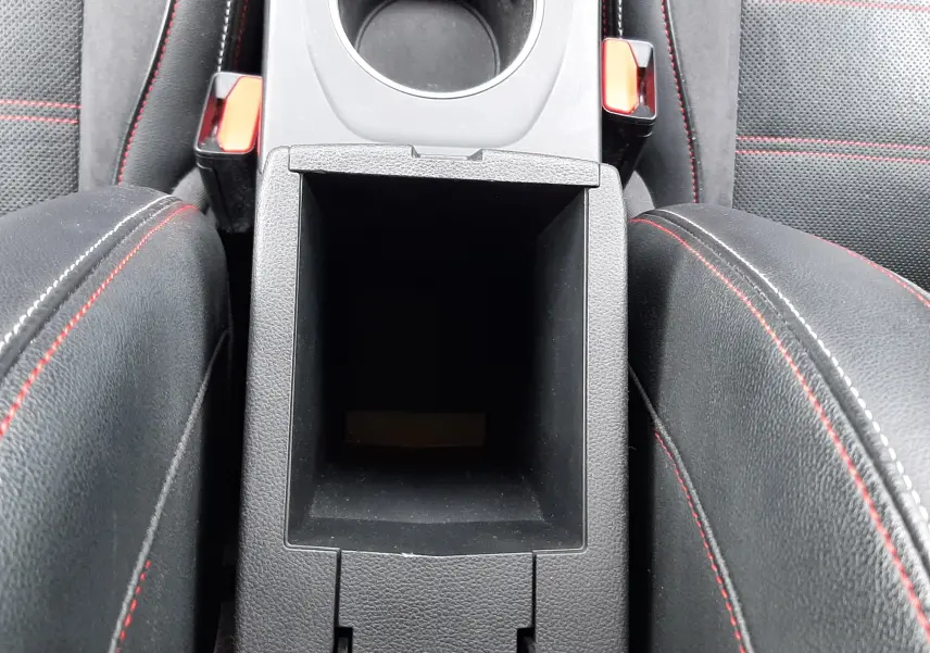 Vue plongeante sur la console centrale ouverte du Renault Arkana E-Tech bleu Zanzibar, avec sièges noirs à surpiqûres rouges visibles.