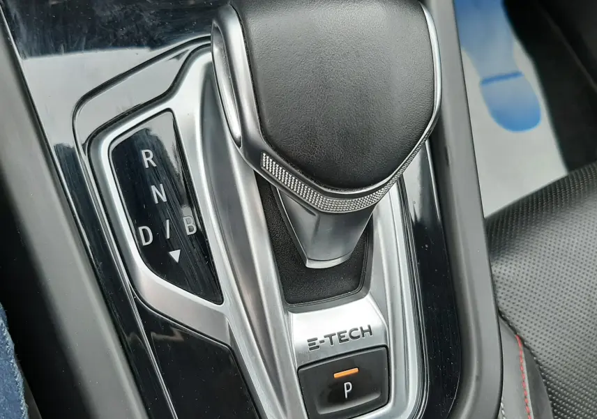Gros plan sur la commande de boîte automatique E-TECH du Renault Arkana, avec levier en cuir noir et console brillante.