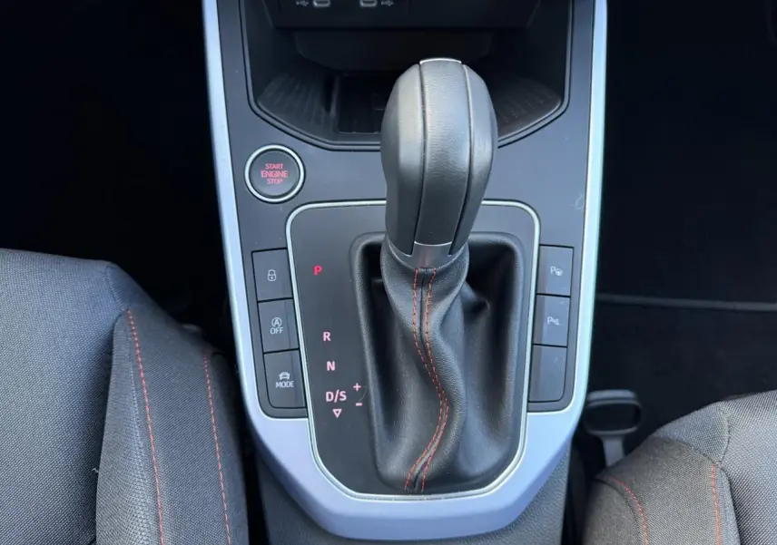 Gros plan sur la console centrale et levier de vitesse noir avec surpiqûres rouges du SEAT Arona 2024.