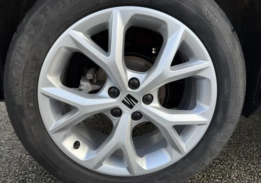 Gros plan sur la jante alliage argentée avec logo SEAT, pneu Goodyear monté sur un SEAT Arona rouge.